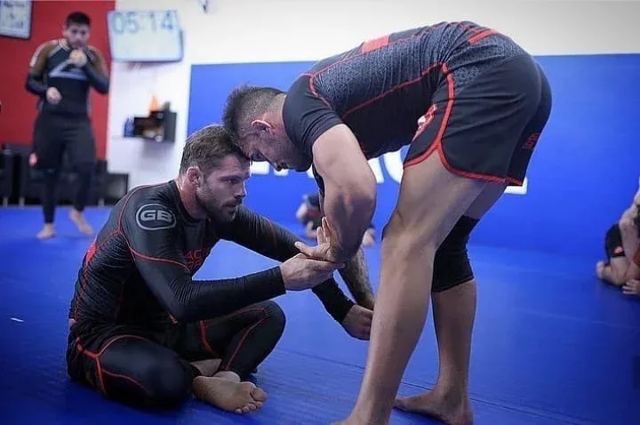Deux pratiquants en tenue no-gi travaillent une technique de jambes